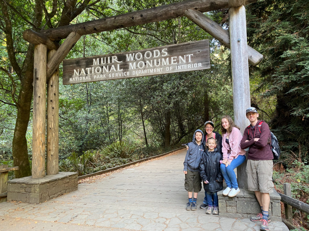 Family posing at the entry to Muir Woods National Monument near San Francisco on a day tour with Spark Experiences
